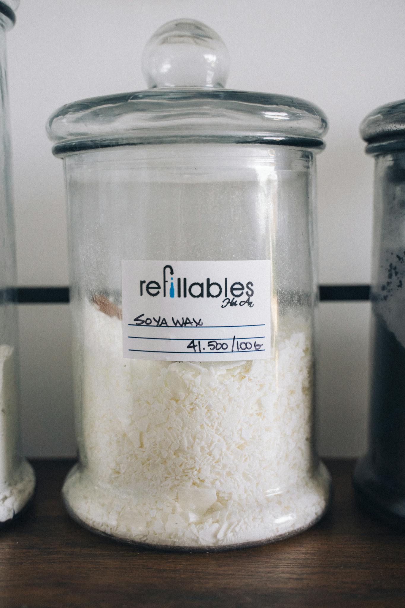 Close-up of a glass jar filled with soya wax, emphasizing eco-friendly packaging and refillable concept.