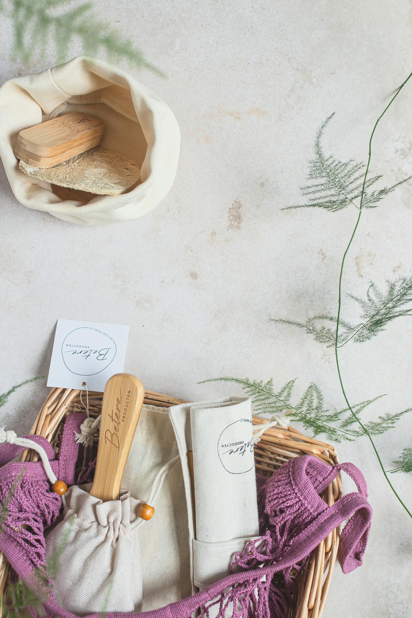 Sustainable zero waste products in a basket with greenery on a white background.
