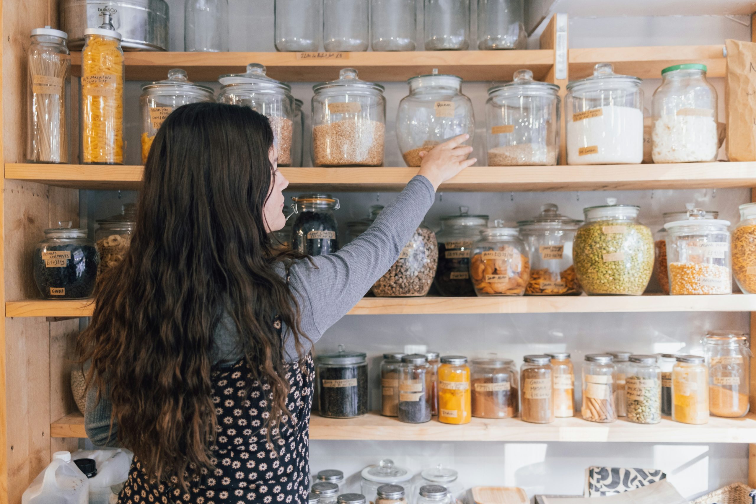 Glass jars of bulk pantry staples on wooden shelves