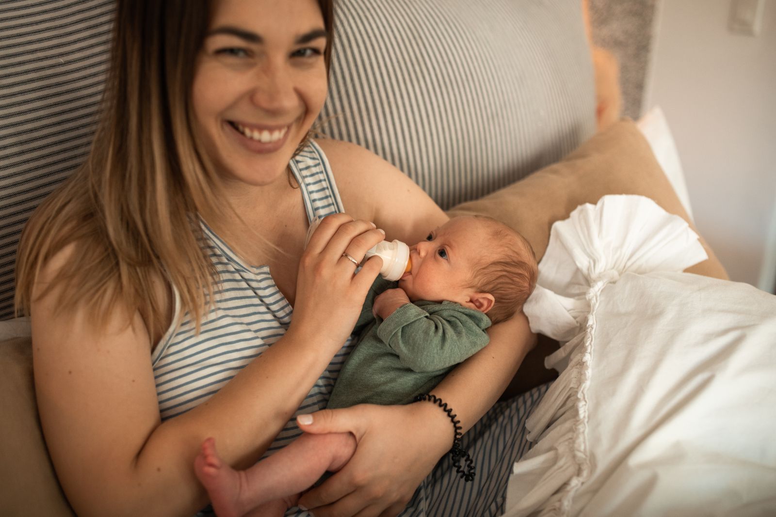 Mother bottle-feeding her newborn on a couch