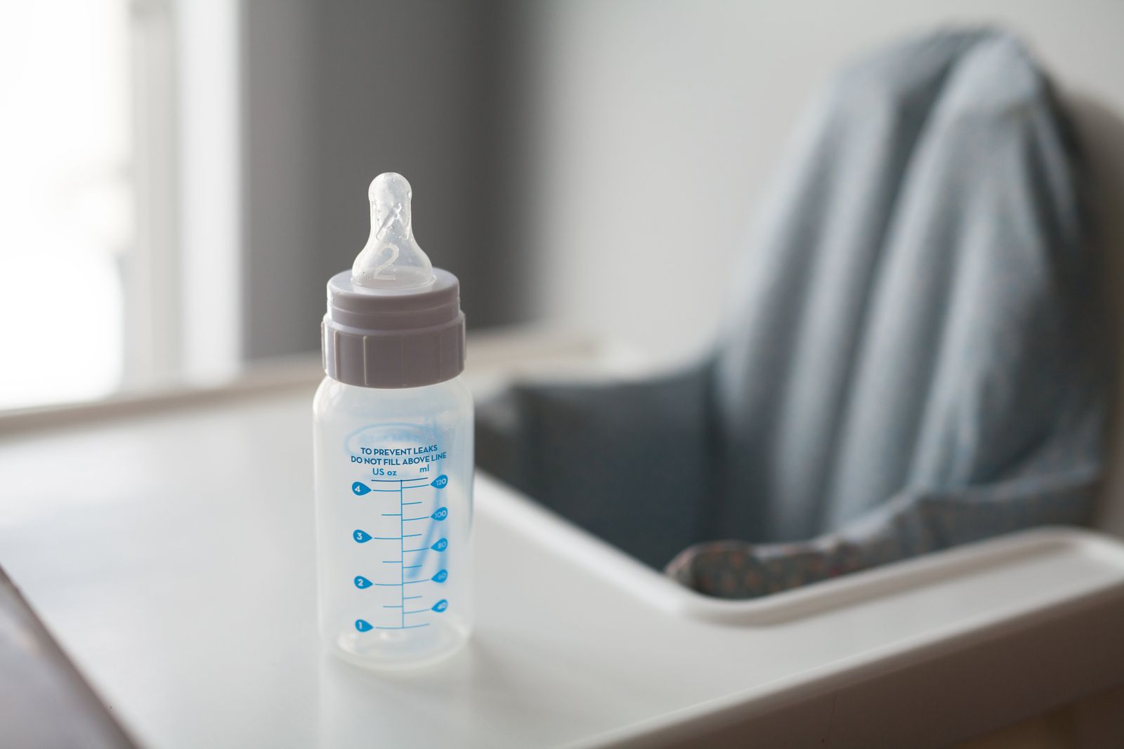 Plastic baby bottle standing on a high chair tray