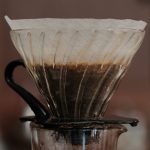 Coffee brewing through a paper filter in a glass pour-over dripper